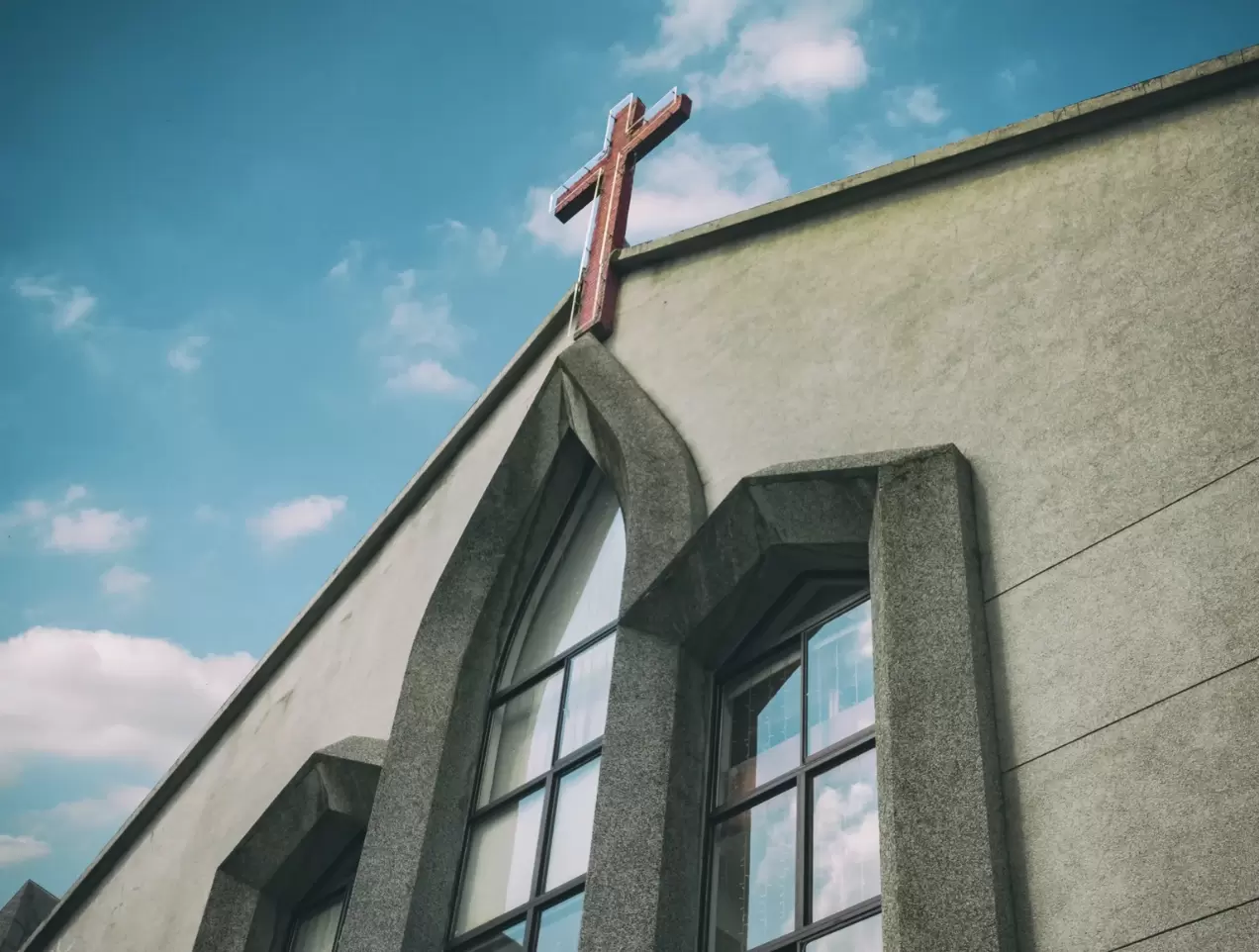 Front of a church building with a cross and blue sky in the background