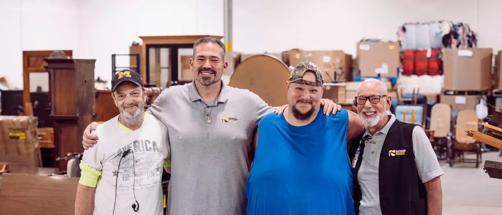 four men standing with their arms around each others shoulders in a thrift store sorting room