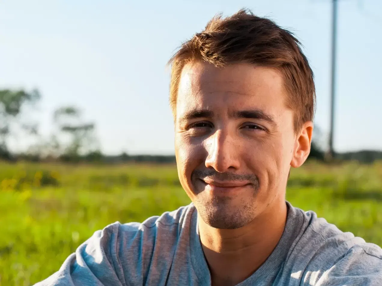 Close up of a man smiling with grass in the background