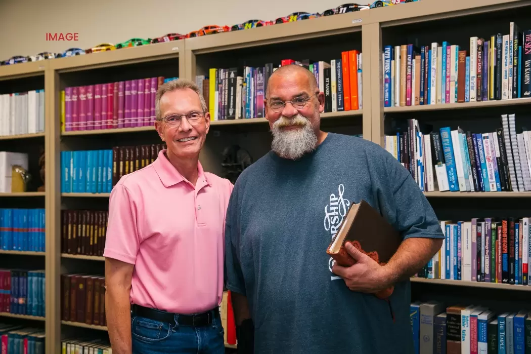 two men standing in front of shelves of books