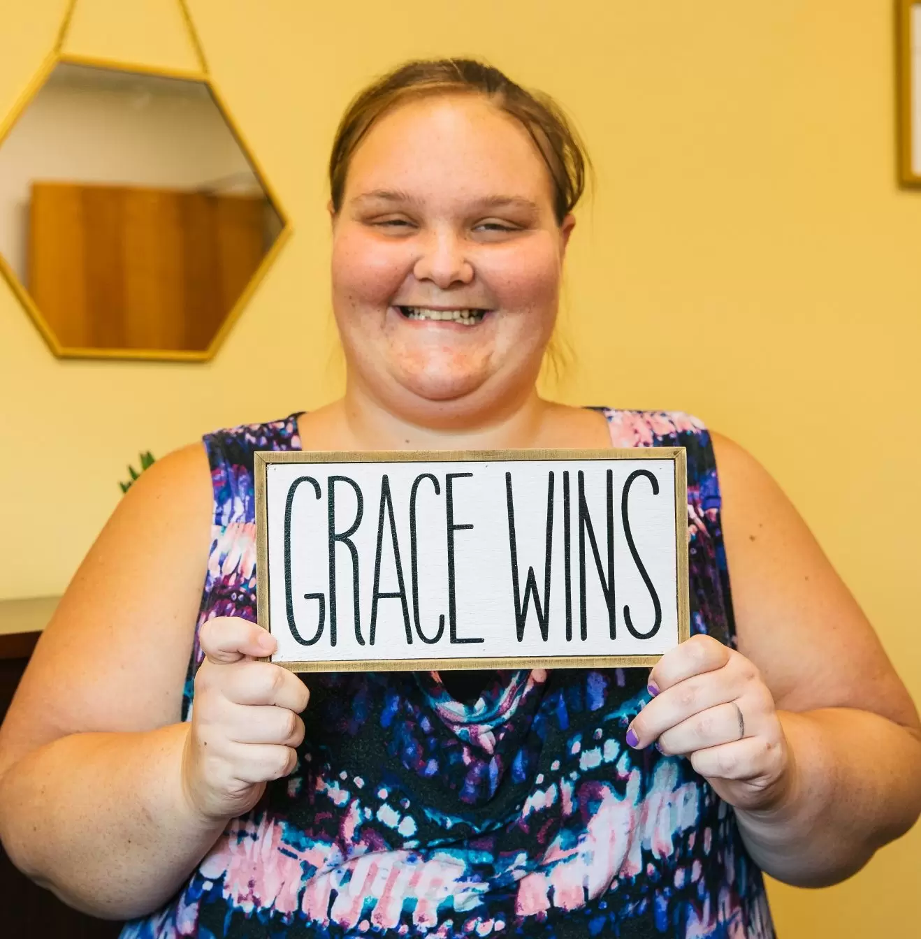 Young woman holding a sign that says, "Grace Wins"