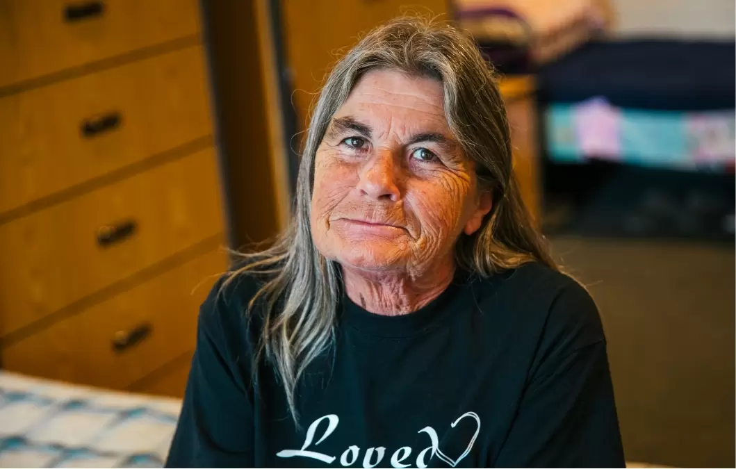 Woman sitting in a shelter room wearing a tshirt that says "Loved"