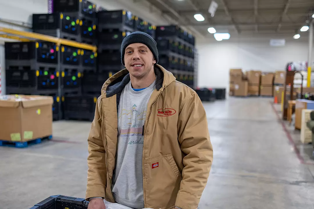 man wearing a beanie and tan jacket in a warehouse