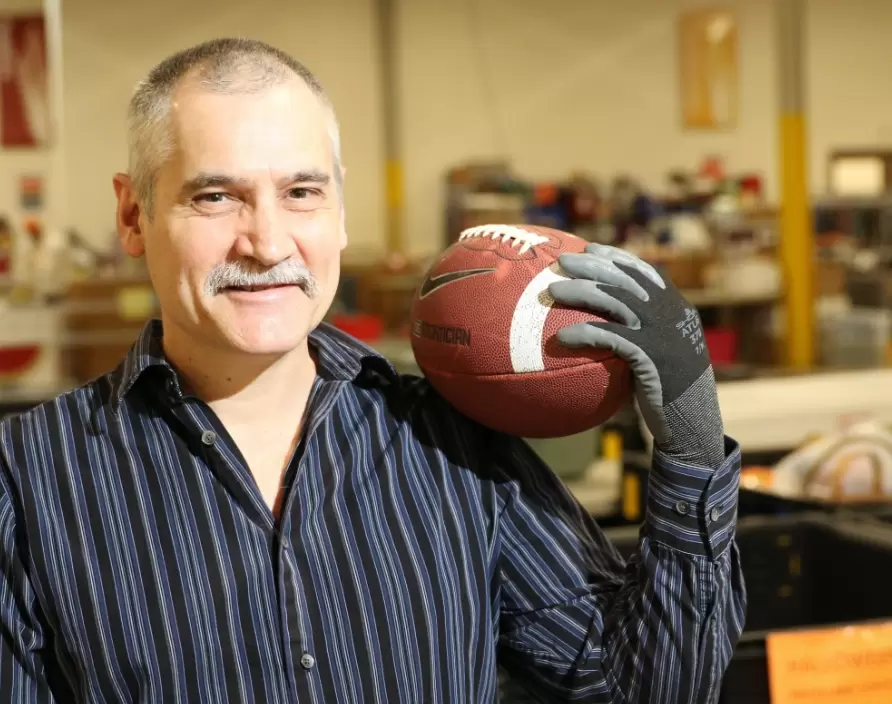 Man holding a football and working at the thrift store