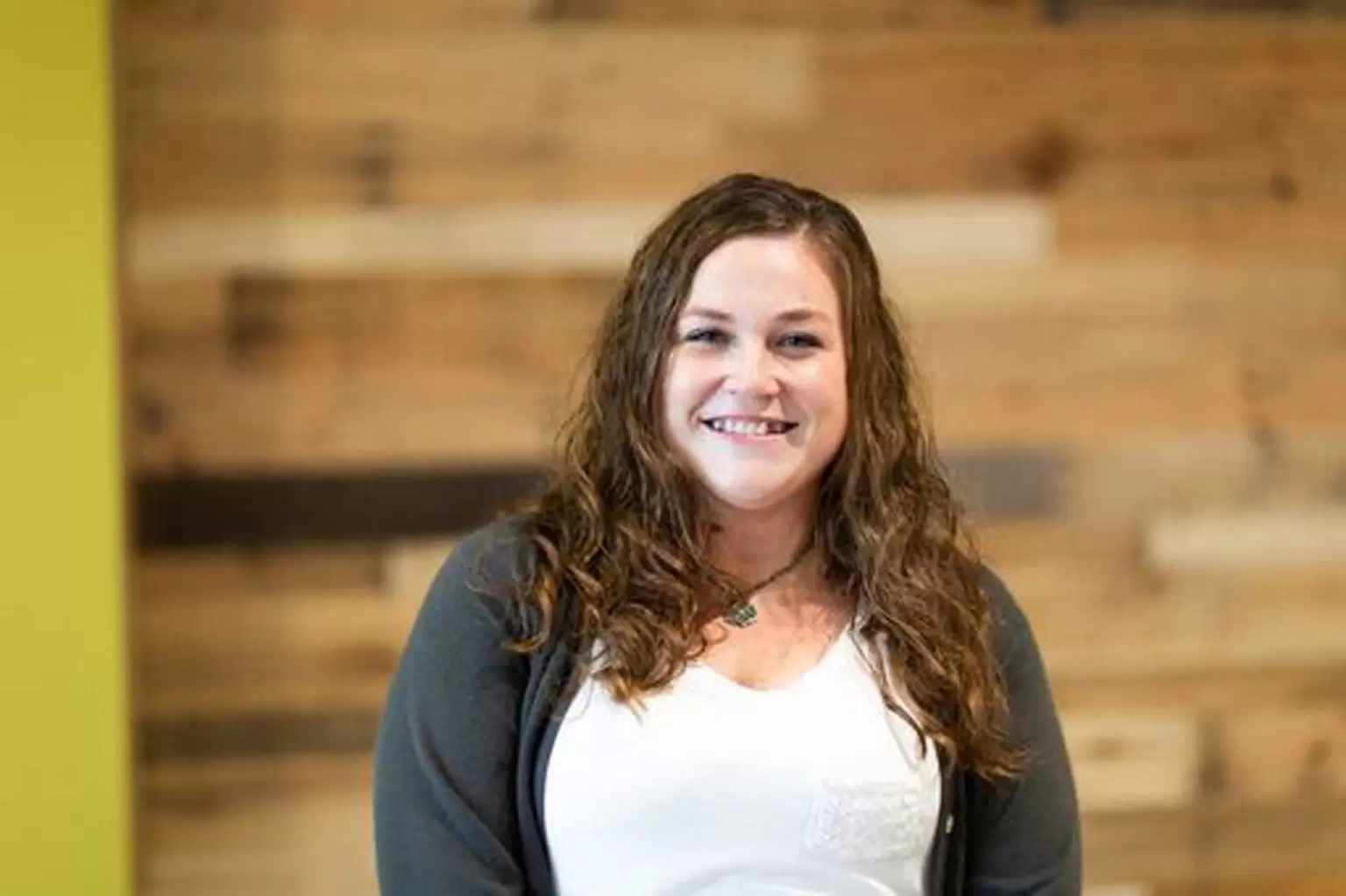 Lisa smiling in front of a pallet wall