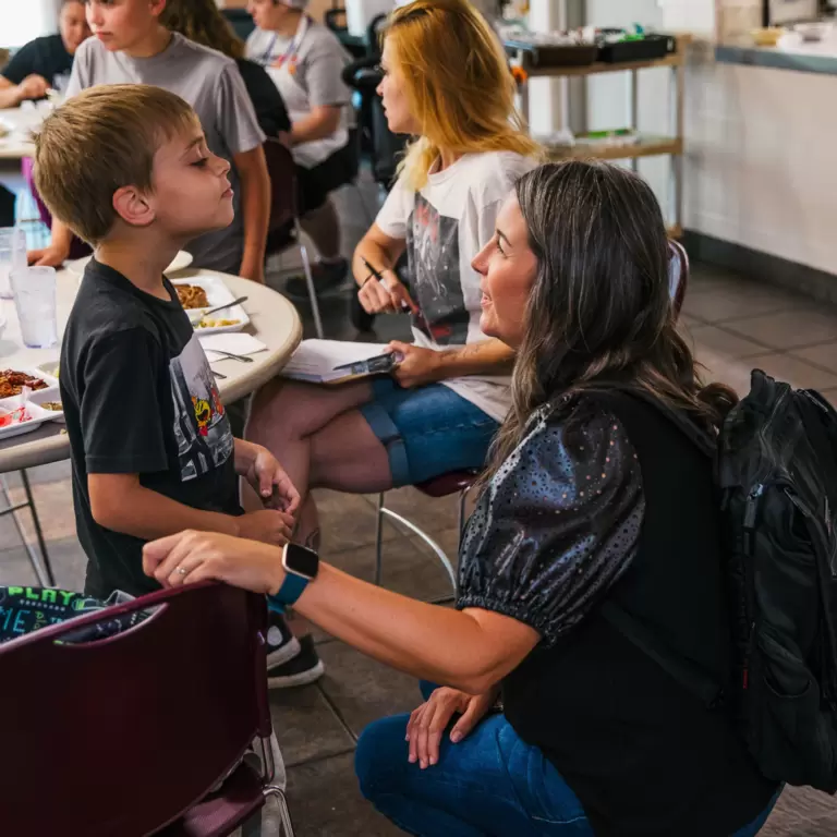 woman kneeling down and talking to a little boy